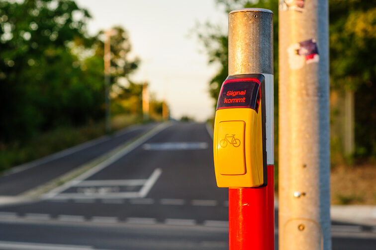 Flashing request button for cyclists. Bicycle lane blurred.