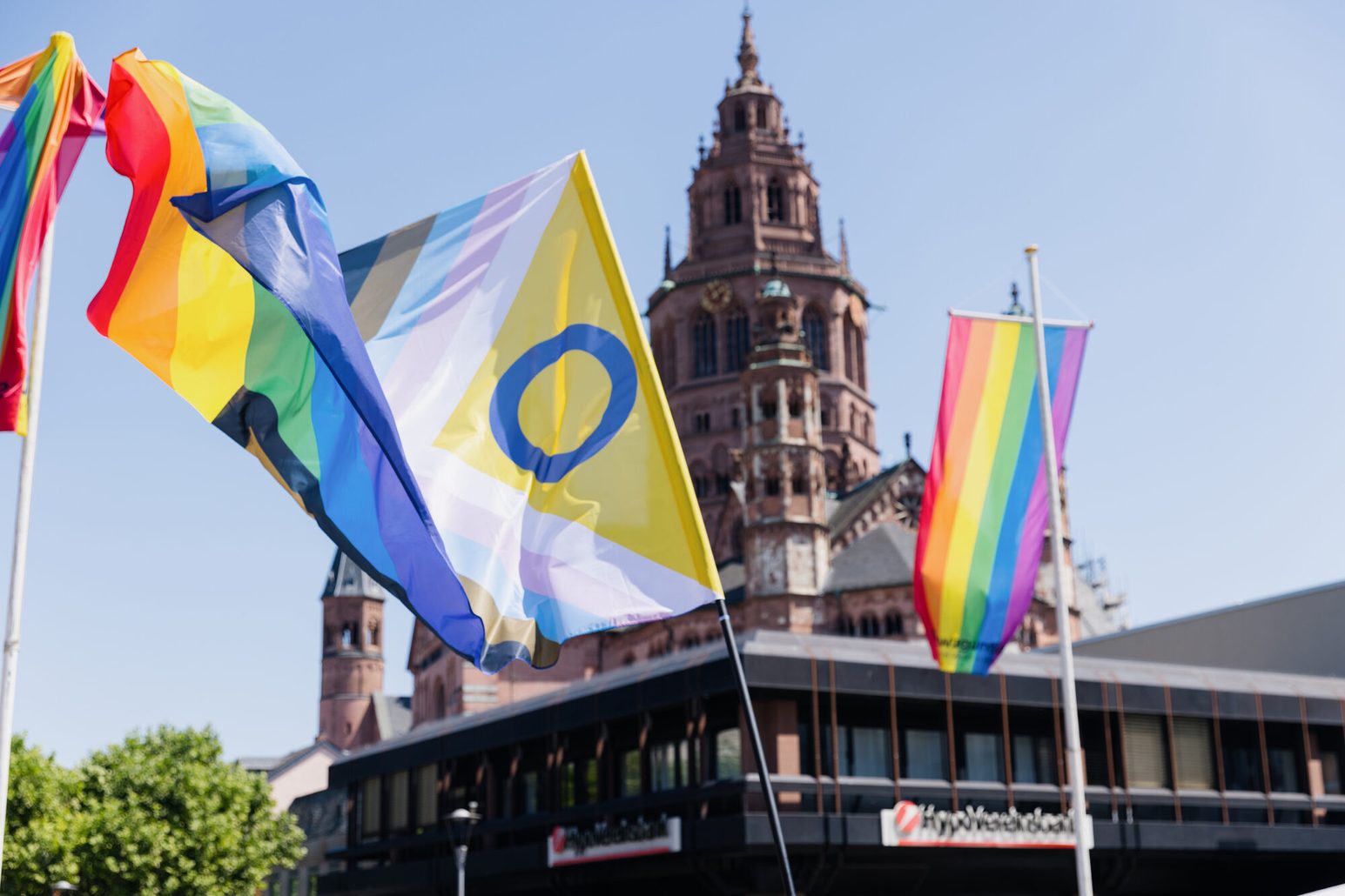The rainbow flag and the Progress flag fluttering in the wind in front of Mainz Cathedral