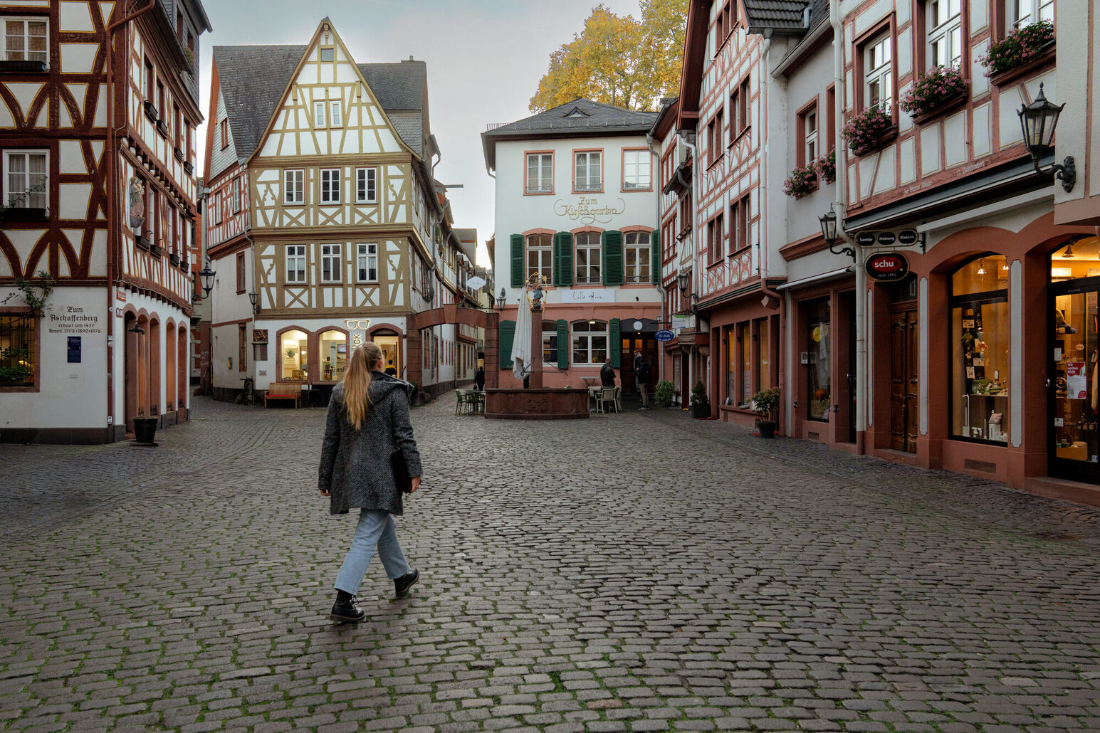 Eine Passantin in der Mainzer Altstadt, umgeben von Fachwerkhäusern