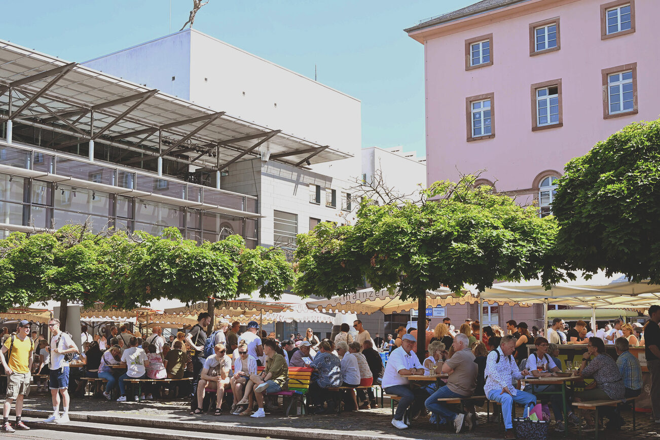 Les visiteurs du Marktfrühstück sont assis sur les bancs de la Tritonplatz.